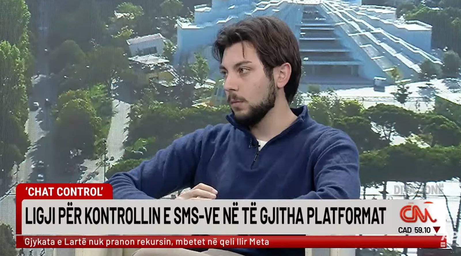 Television screen showing a young man in a studio interview, with an Albanian caption about Chat Control